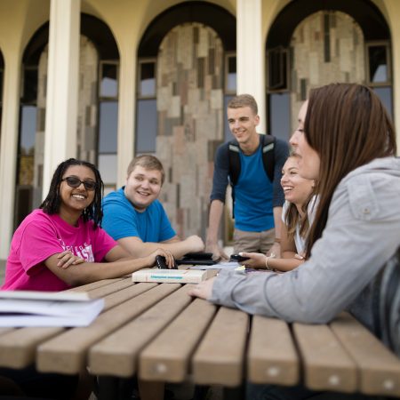 Students gather at a picnic table outside of the Science Center