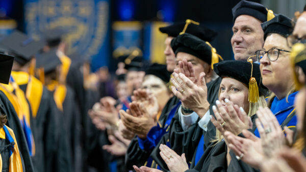 Faculty and staff clapping for graduates at Commencement.