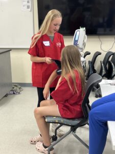 Scrubs Camp participants use blood pressure machine.