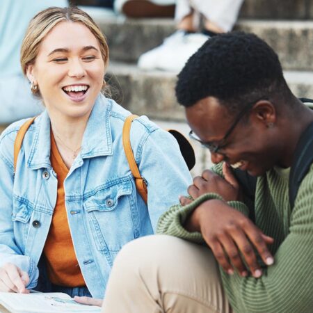 St. Scholastica students sit and laugh together on stone stairs.