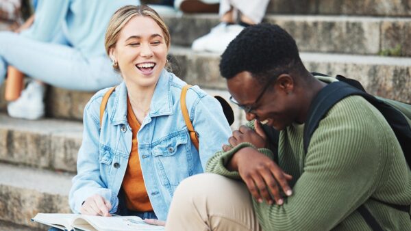 St. Scholastica students sit and laugh together on stone stairs.