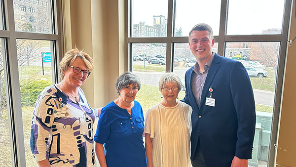 Photo of Luke Wessberg with 3 women in front of a window overlooking the duluth campus.