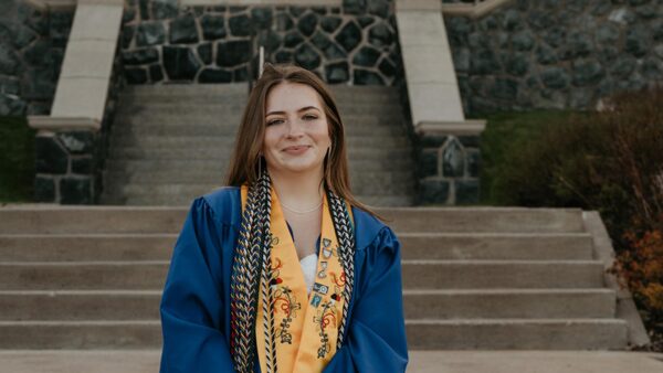 Portrait of Renee Booth in front of Tower Hall in her graduation gown