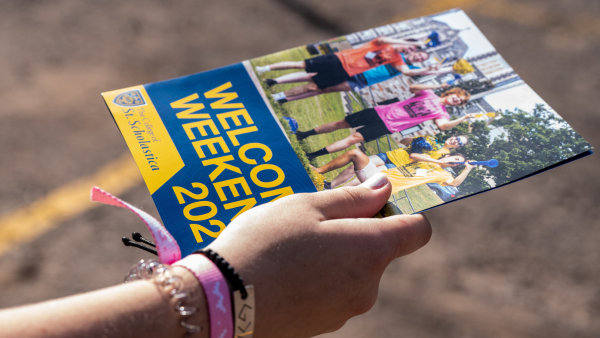 Individual holds a brochure for Welcome Weekend.