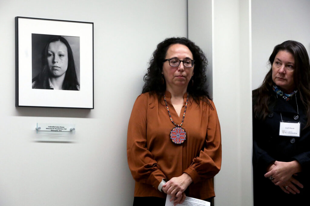 Amy Bergstrom stands next to a photograph at the AIM exhibit.