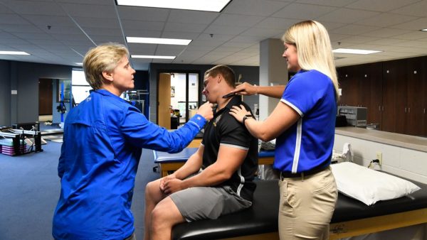 St. Scholastica professor teaching an athletic training technique in a lab setting.