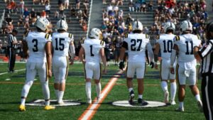 Six football players walk on the football field.