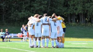 Players of the men's soccer team huddle together on the field.