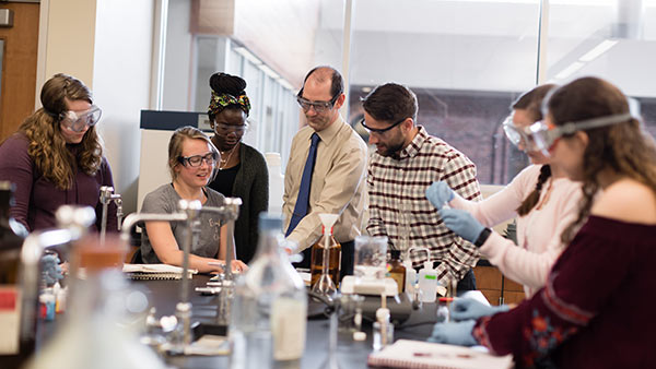 Students being advised by a St. Scholastica professor in a Chemistry lab.