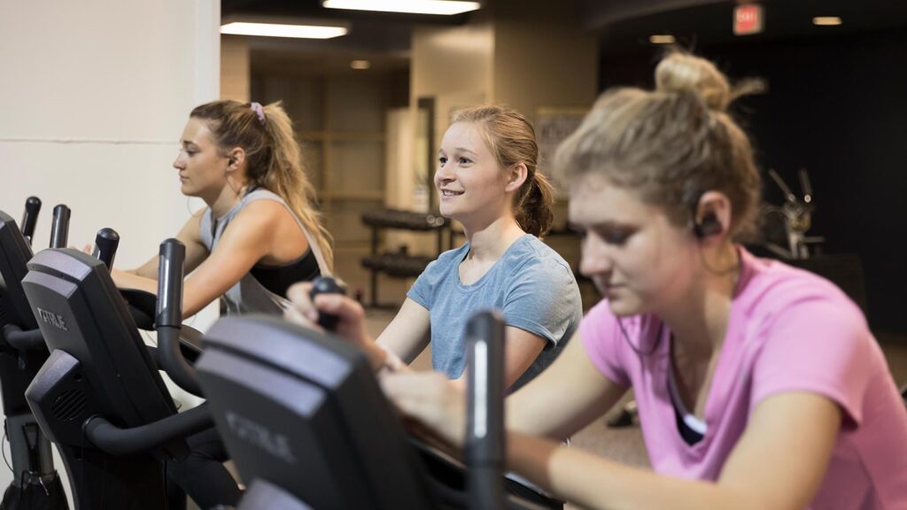 A group of 3 students working out in the Burns Wellness Commons fitness center.