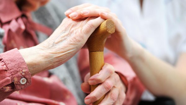 A caregiver holding and elderly person's hand.