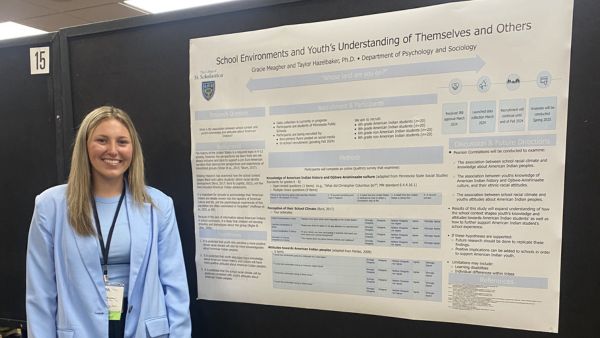 Gracie Meagher smiles in front of her research poster at a conference.