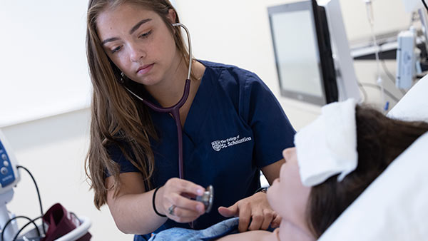 A St. Scholastica Nursing student checking a patient's heartbeat in the Nursing Simulation Lab.