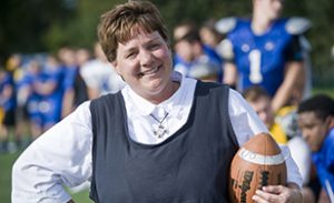 Sister Lisa Maurer smiling and holding a football