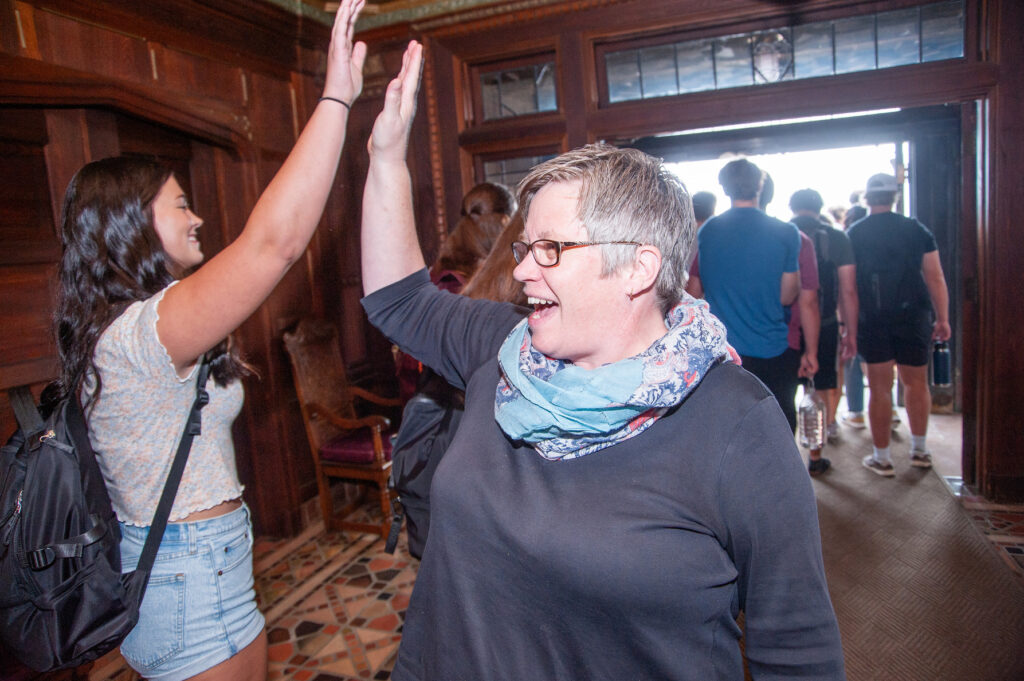 Student receives a highfive from staff member in the entry of Tower Hall.