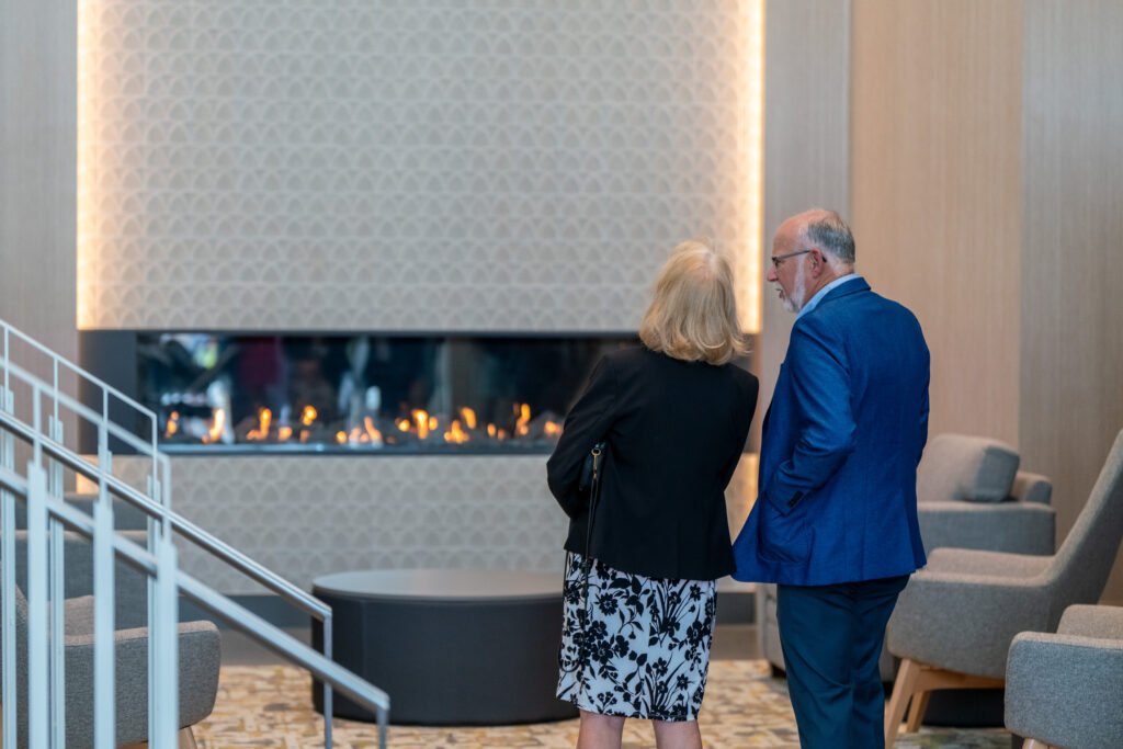 Two individuals tour the new Student Center and stop to observe the new fireplace.