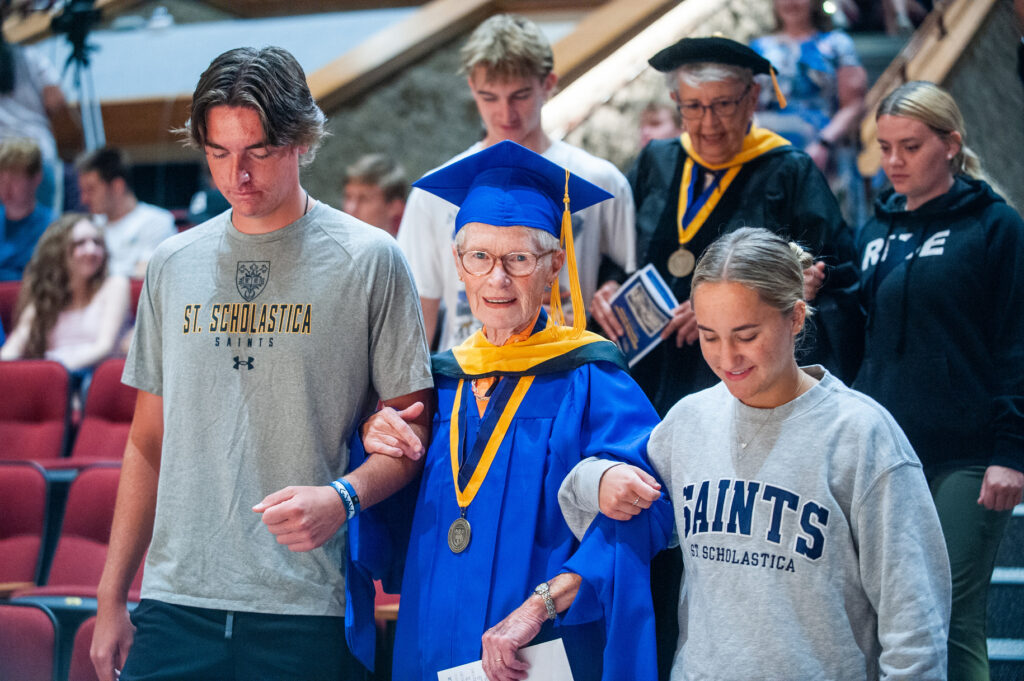 Students assist alumni going down the stairs of Mitchell Auditorium.